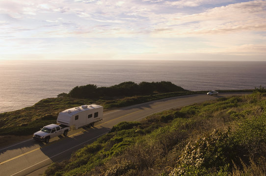 Truck pulling camper on coastal highway