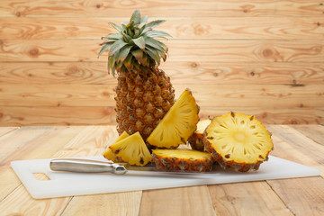 Fototapeta na wymiar Pineapple slices with cutting board on wood table