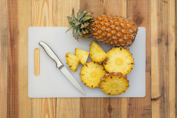 Pineapple slices with cutting board on wood table,Top view