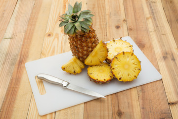 Pineapple slices with cutting board on wood table
