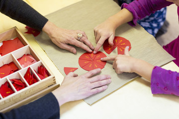 Close up of Caucasian Montessori teacher and student solving puzzle