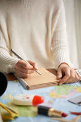 Woman writing in notepad when planning vacation