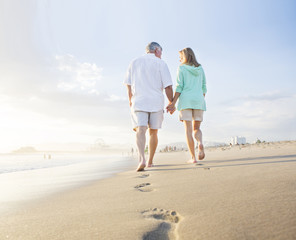 Caucasian couple leaving footprints on beach