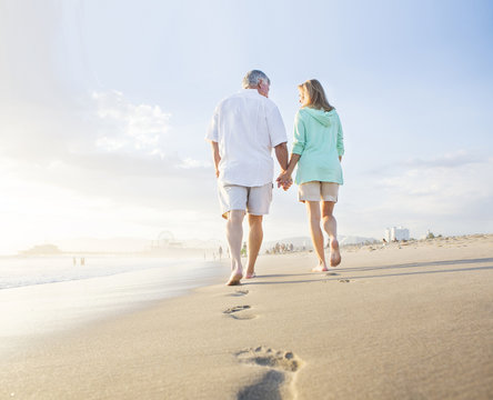 Caucasian couple leaving footprints on beach
