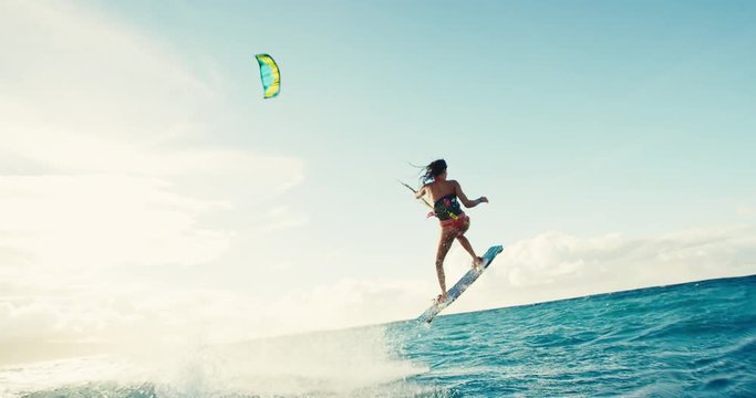 Beautiful young woman kiteboarding at sunset in slow motion, active lifestyle extreme sport