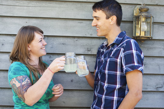 Couple toasting drinks while standing against wall