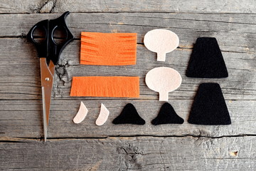 Cut felt parts for sewing witch toy, scissors on old wooden background. How to make a Halloween...