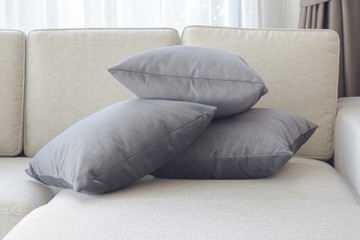 Stacking dark gray pillows on beige sofa