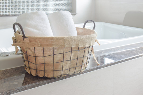 Towels in basket next to white bathtub in the bathroom