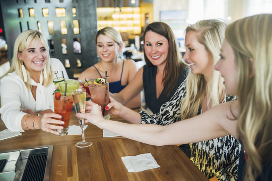 Women toasting at bar with cocktails
