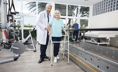 Male Physiotherapist Helping Female Patient With Walker