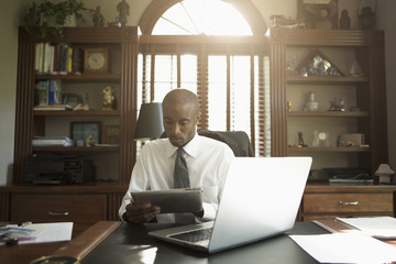 Black doctor using digital tablet in office