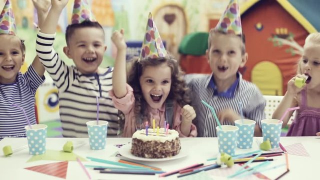 children blowing out candles on birthday cake