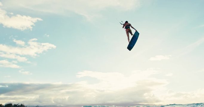 Beautiful young woman kiteboarding at sunset in slow motion, active lifestyle extreme sport