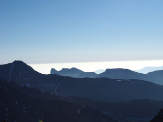 Naklejka na ściany i meble Mountains and Hills panoramic View with many stacked foggy smoky ranges highlighted back light Sunshine