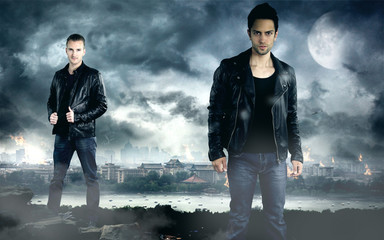 two handsome men posing in front of the dark city