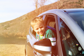 happy little boy travel by car in autumn nature