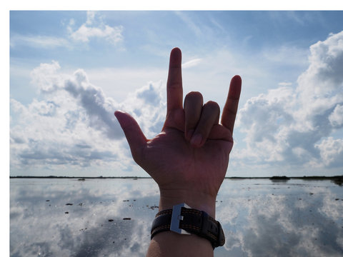 Hand with love symbol on beautiful sky and reflection in the river background, silhouette
