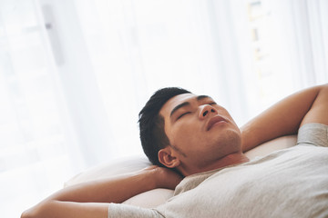 Asian young man relaxing in bed in the morning