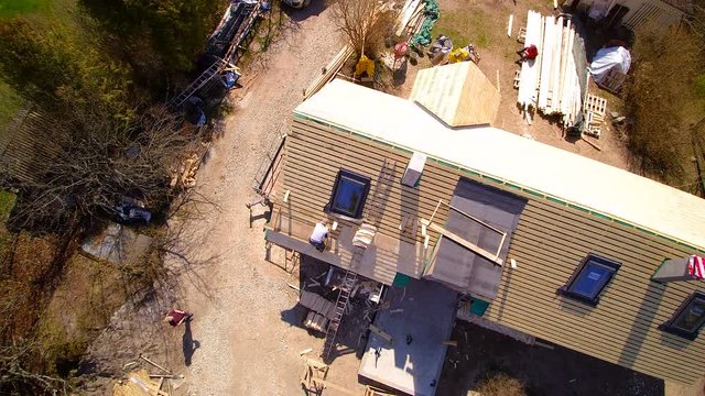 The aerial view of the wooden cabin house with the shingles being installed by the roofer