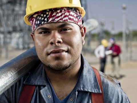 Close-up of construction worker carrying pipe