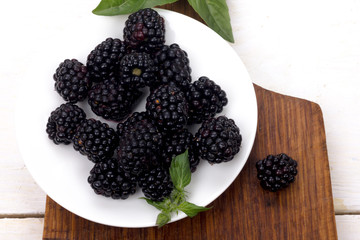 blackberry berries on a white plate with wood background