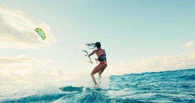 Beautiful young woman kiteboarding at sunset in slow motion, active lifestyle extreme sport