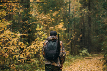 Naklejka premium Male hunter in the autumn forest. A man holding a gun.