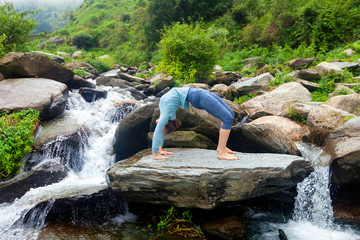 Woman doing Ashtanga Vinyasa Yoga asana Urdhva Dhanurasana - up