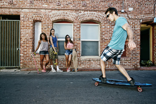 Friends riding longboards on city street