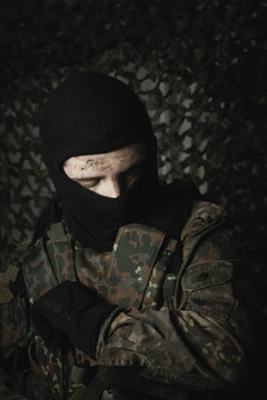 army soldier in uniform with dirty face and balaclava looking si