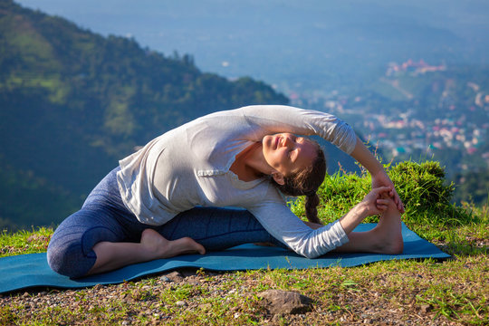 Young sporty fit woman doing Yoga asana parivritta janu sirsasana