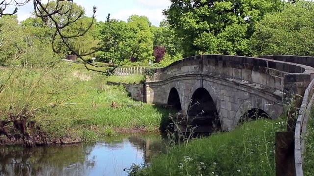 A cyclist rides across a stone bridge over a rver in central England