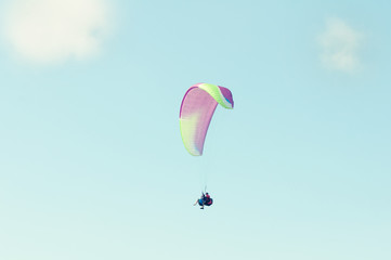 Tandem paragliders flying up in the blue sky