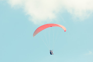 Paraglider flying up with red wing
