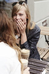 Ladies laughing over coffee at pavement cafe