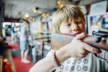 Boy aiming rifle in arcade shooting game