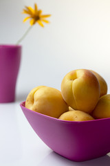 Apricots in pink drinking bowl and orang flower in pink vase