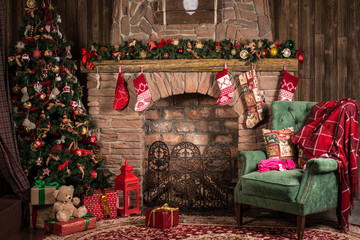 Новогодние или Рождественские декорации, кресло с пледом рядом с камином и нарядной елкой 