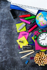 School stationery, pencil, pen, note, alarm clock on grunge chalkboard