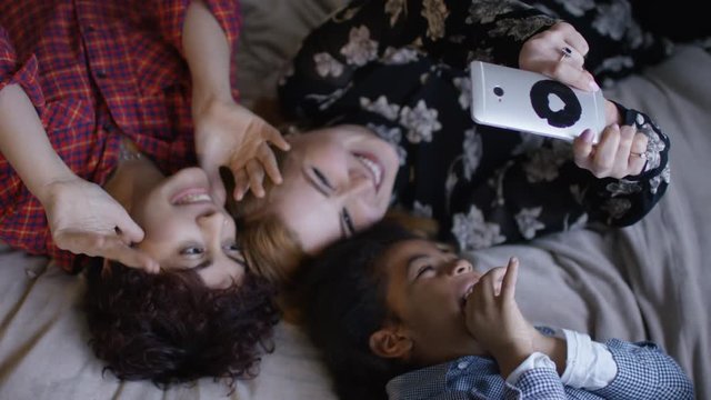  Gay female couple taking selfie in bedroom with young son