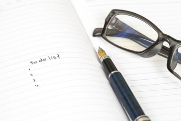 Fototapeta premium writing to do list on notebook page with pen on wood background