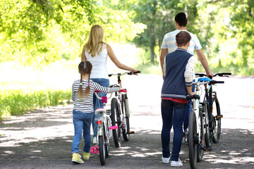 Fototapeta na wymiar Beautiful family with bikes in park