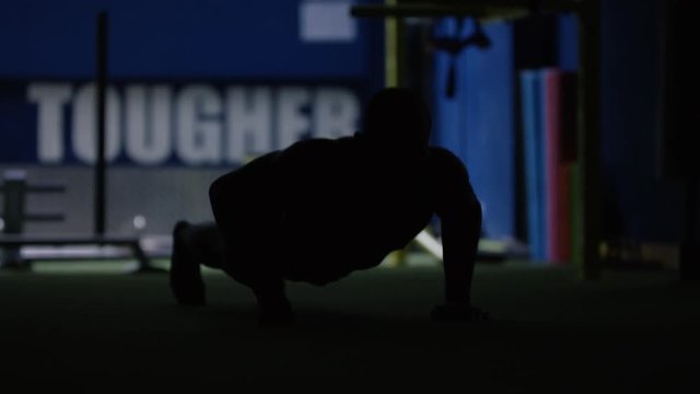 Unrecognizable MMA fighter in silhouette, training alone in dark gym