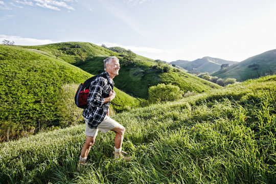 Older Caucasian man walking on grassy hillside