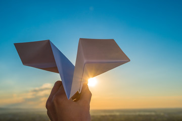 The hand hold paper airplane and launch by the bright sun and picturesque landscape background