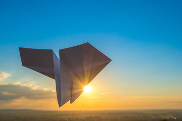 The paper airplane fly on the background of a picturesque sunset