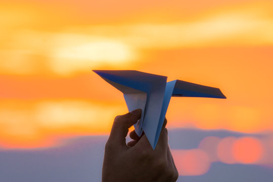 The hand hold paper airplane and launch on the background of picturesque sunset