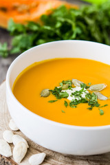 Pumpkin soup and ingredients on rustic wooden background

