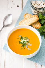 Pumpkin soup and ingredients on white wooden background

